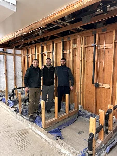 Three ProLine crew members on a commercial re-pipe with the walls opened to the framing