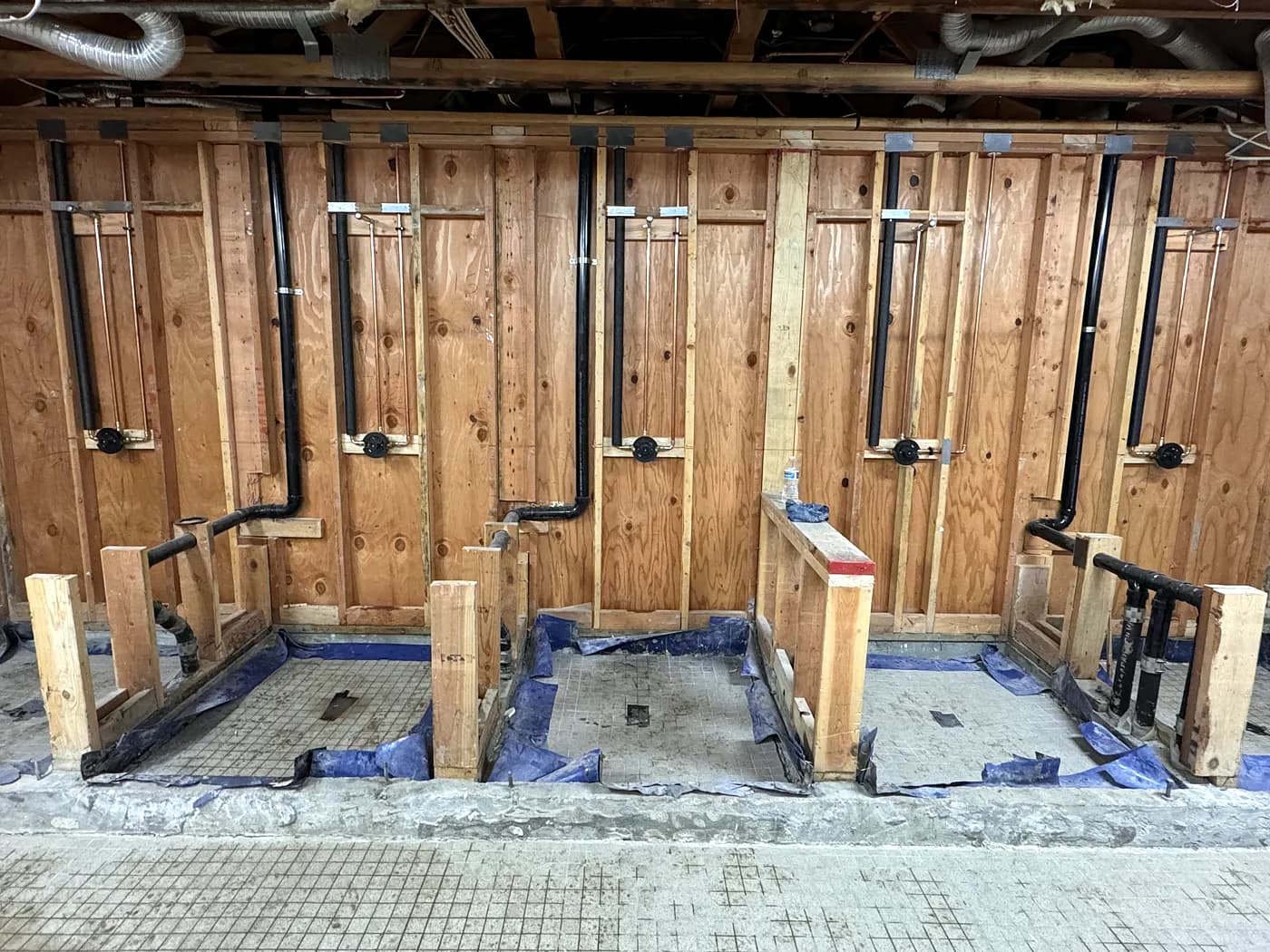 New black drain lines run through opened stud walls in a commercial space