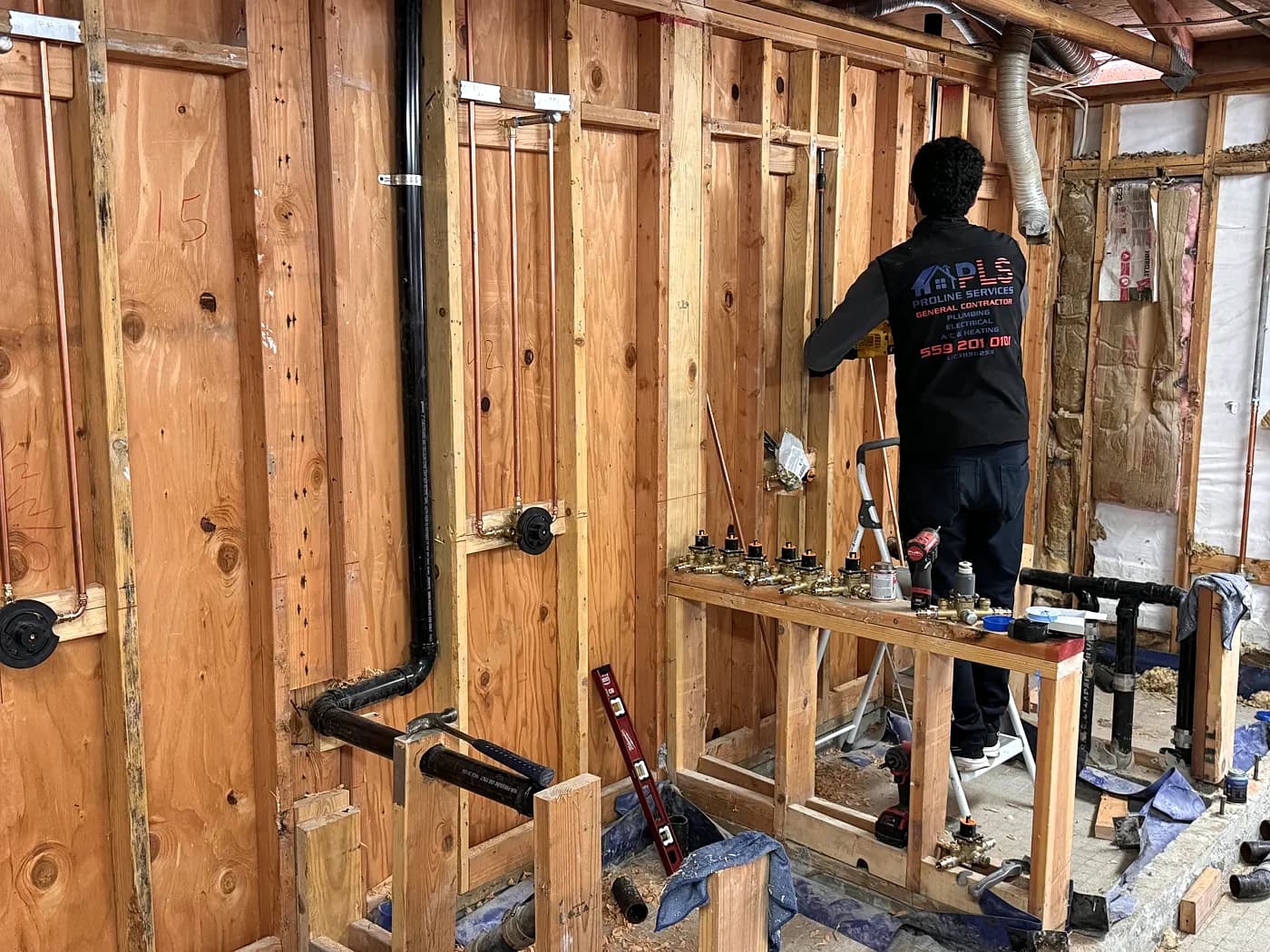 A ProLine plumber working on new piping in an opened commercial wall