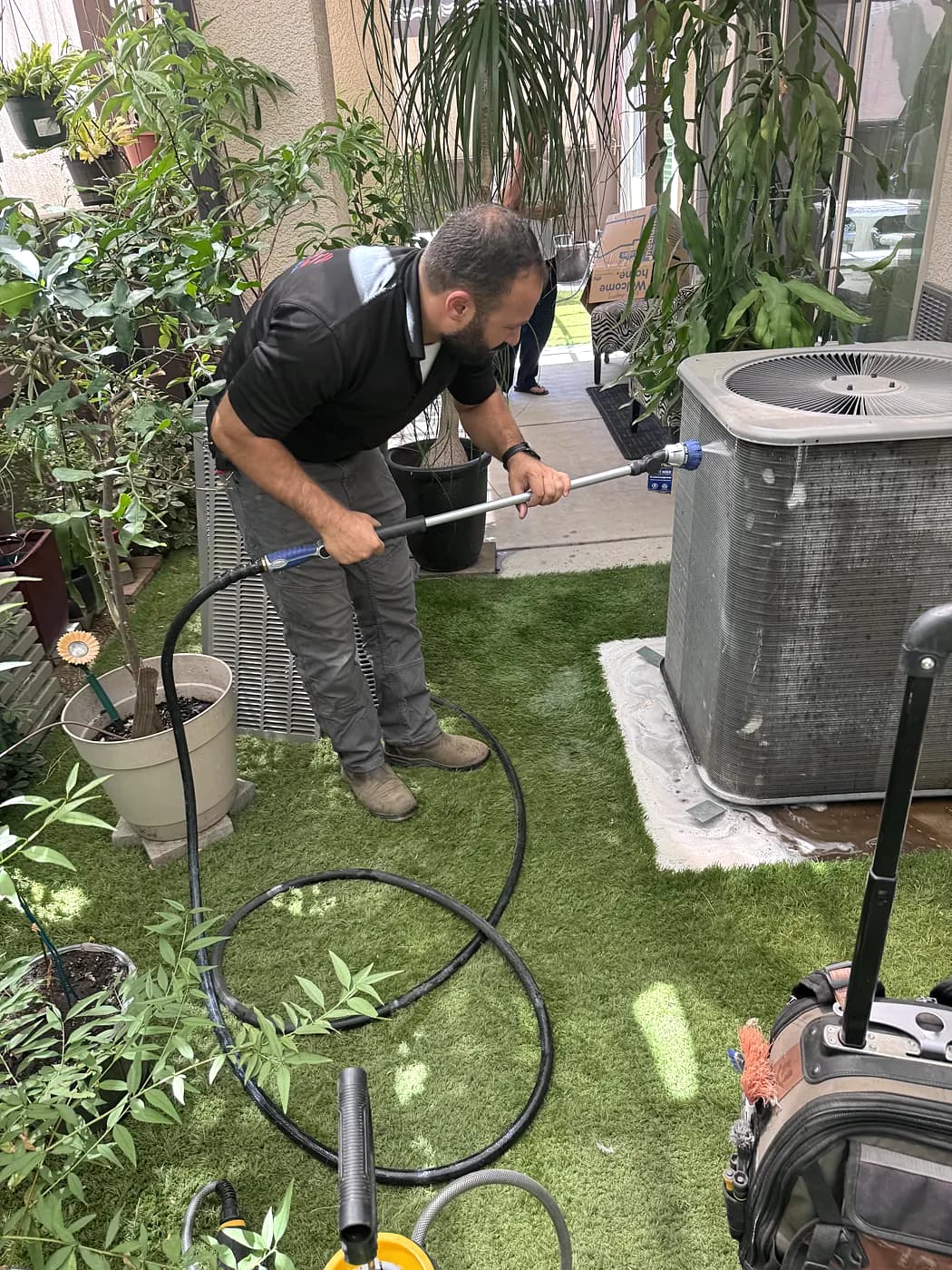 A ProLine technician cleaning an outdoor AC condenser in a backyard
