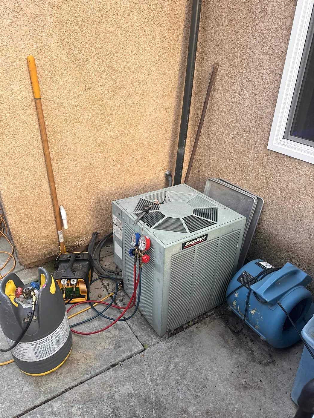 A new AC condenser installed in a side yard, with recovery equipment beside it
