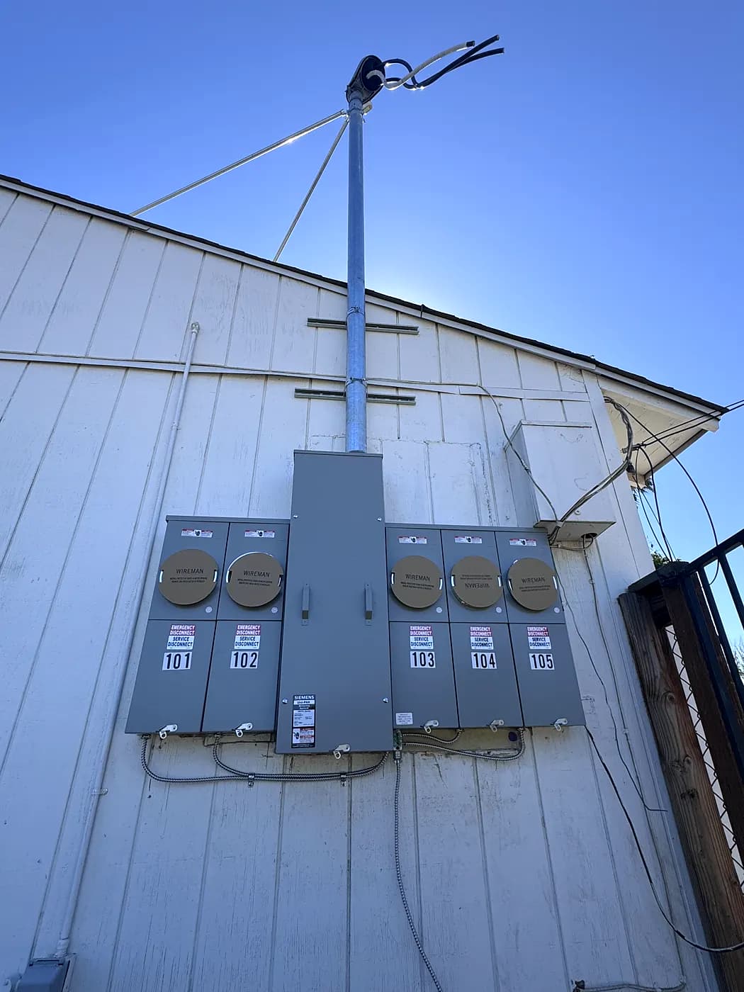 A new 400 amp main panel with five meters on a white exterior wall