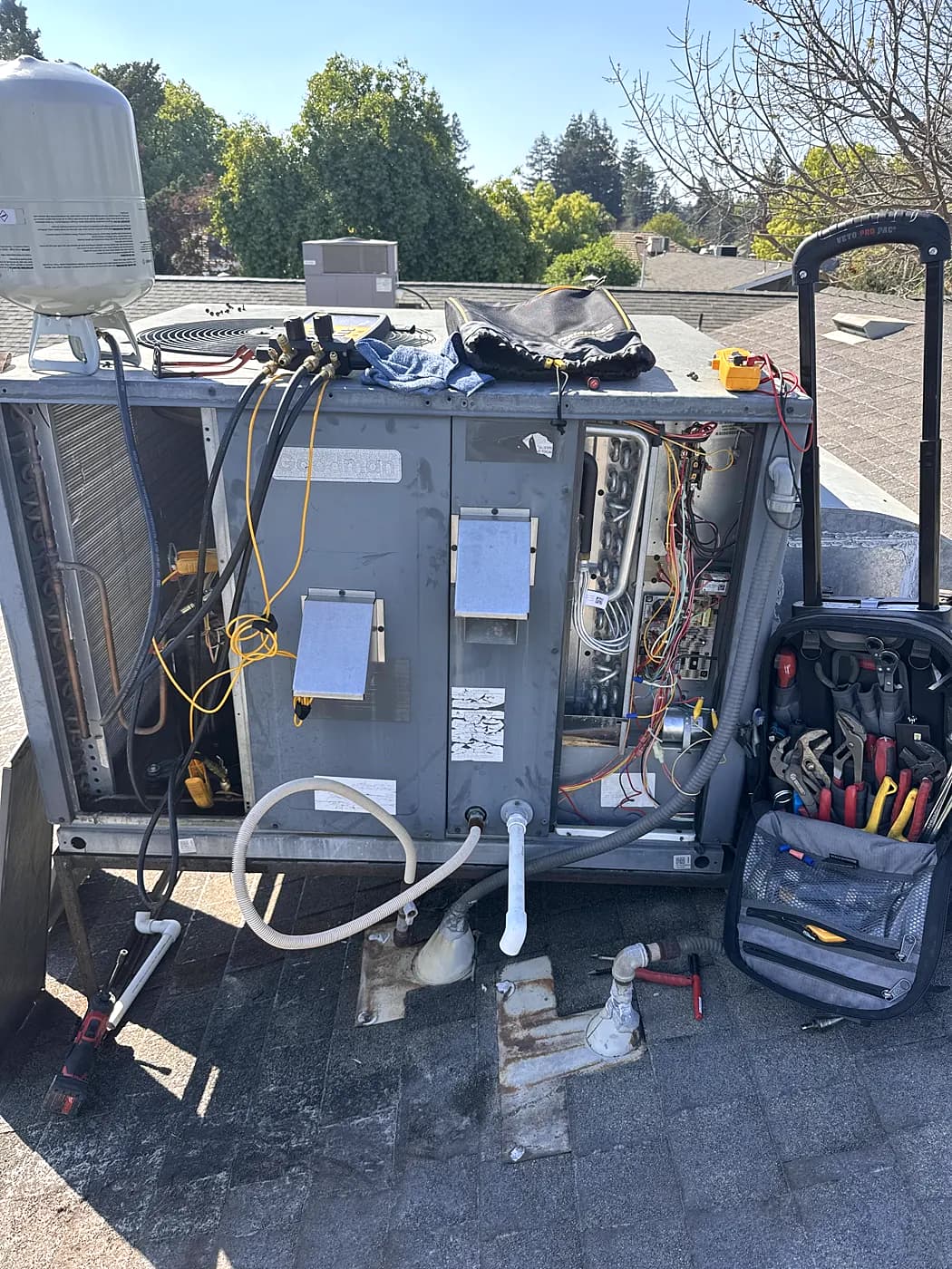 A packaged AC unit opened up for service, with a technician's tool bag