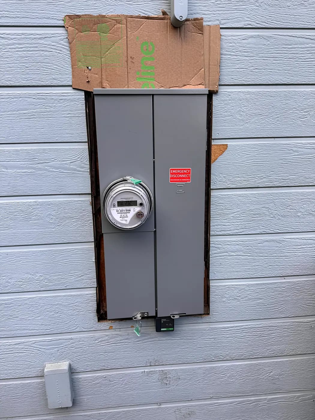 A new 200 amp main panel with its meter on a grey siding wall