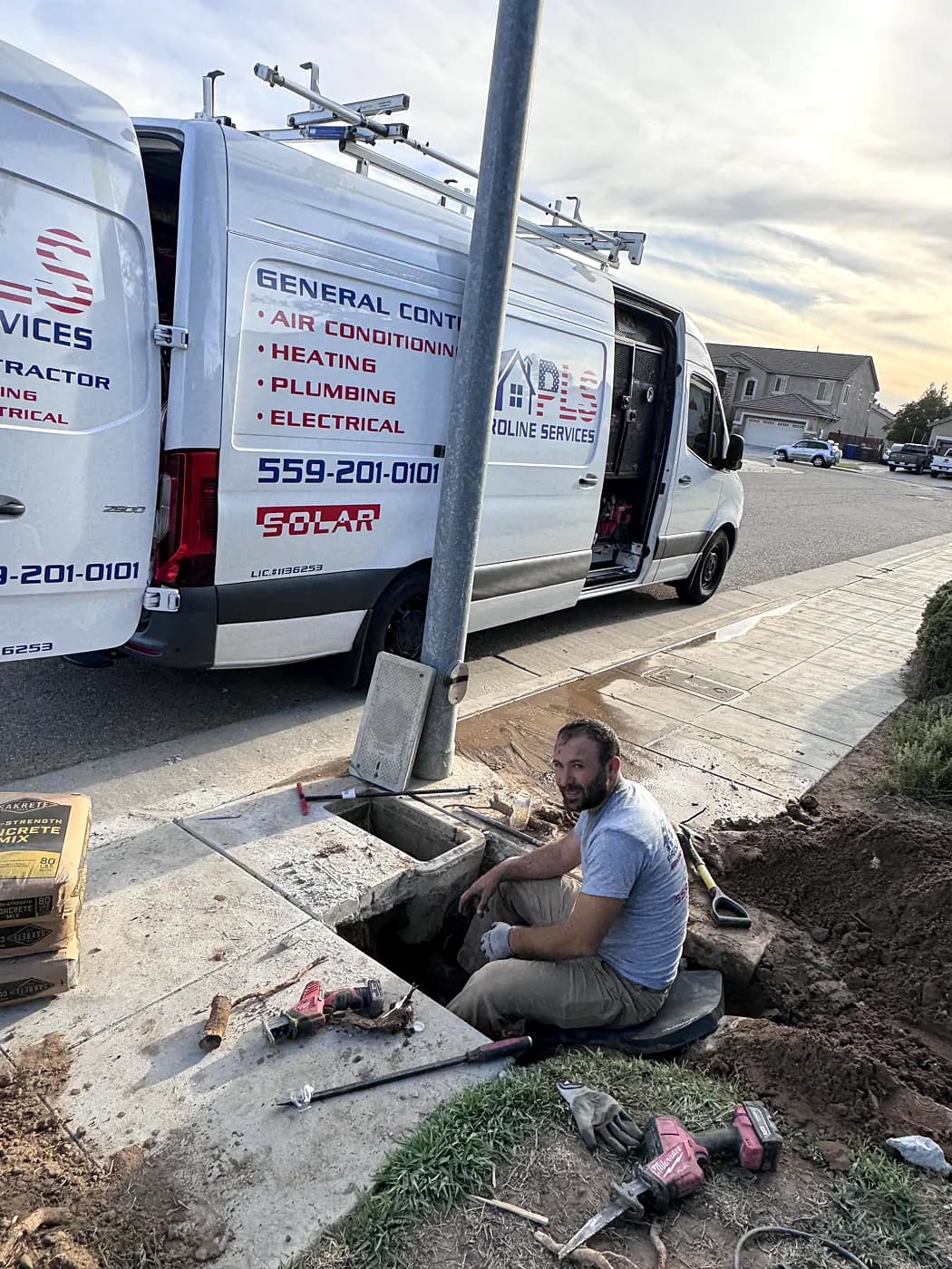 A ProLine plumber in an excavation next to the work van, repairing an underground line
