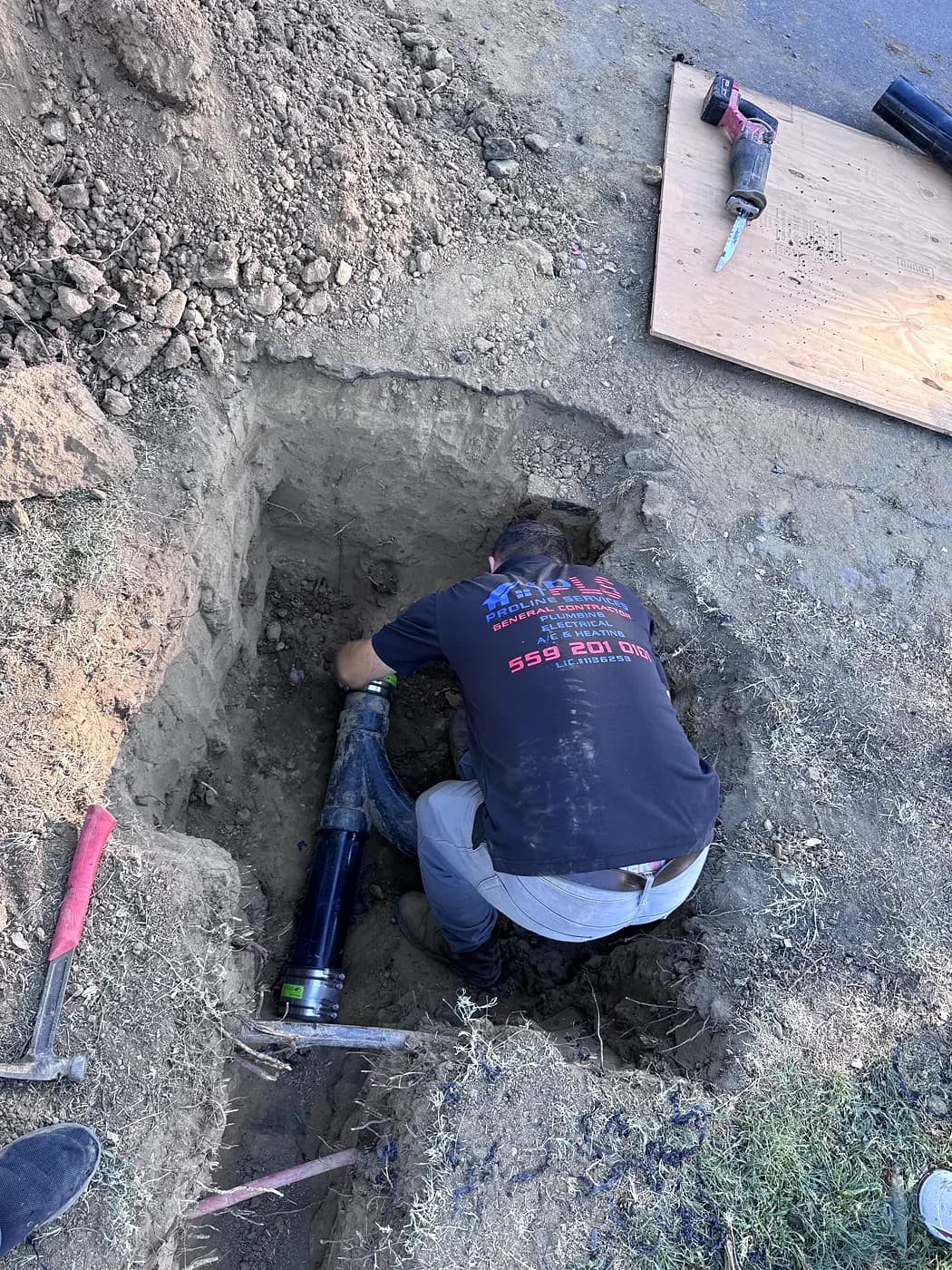 A ProLine plumber working in a trench on an underground pipe repair