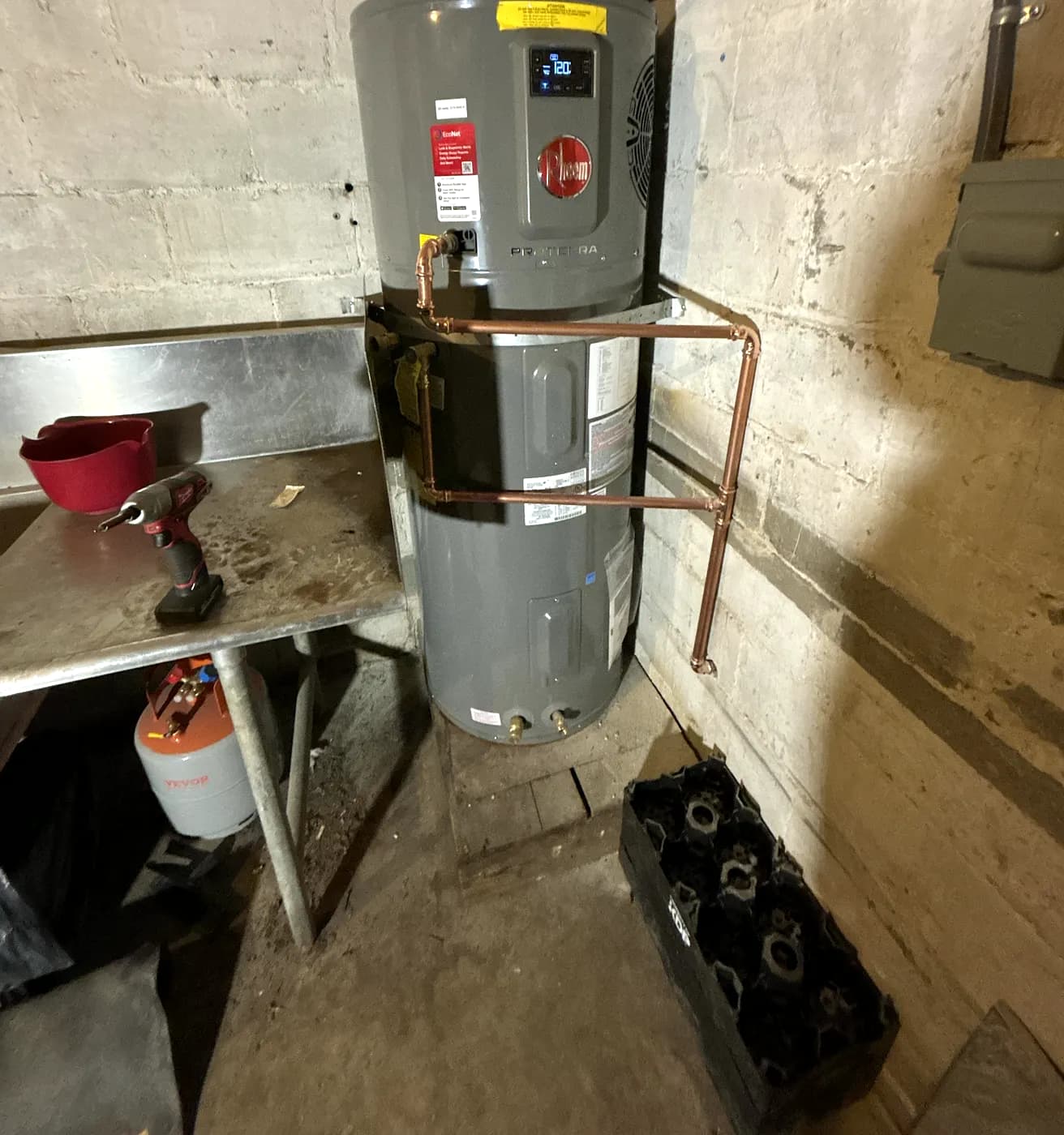 A new water heater with new copper piping beside a work table